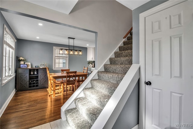 stairs with baseboards, recessed lighting, wood finished floors, and a notable chandelier