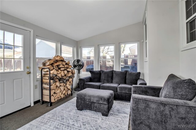 living area featuring dark colored carpet, vaulted ceiling, and a healthy amount of sunlight