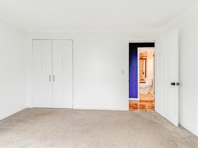 unfurnished bedroom with crown molding, carpet flooring, baseboards, and a closet