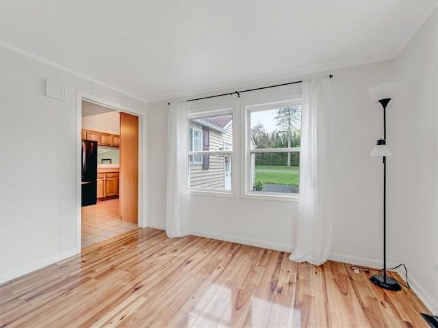 unfurnished room featuring light wood-type flooring, baseboards, and visible vents