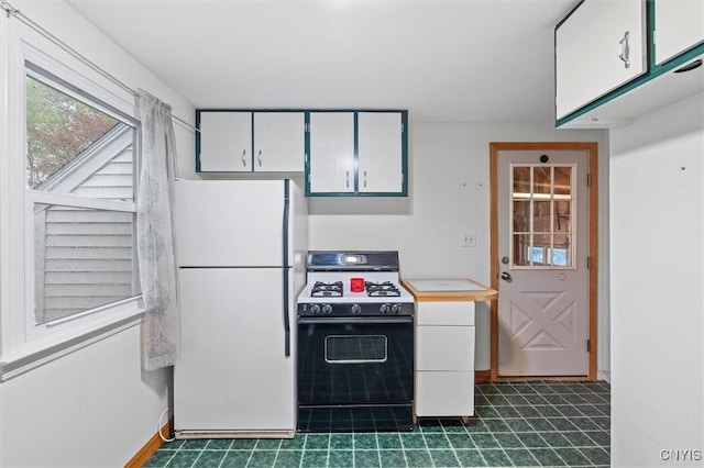 kitchen featuring freestanding refrigerator, white cabinets, range with gas stovetop, and light countertops