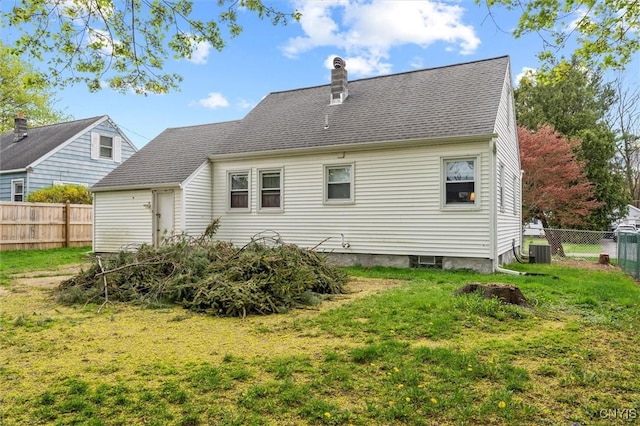 rear view of property featuring central AC, a fenced backyard, a chimney, a shingled roof, and a lawn