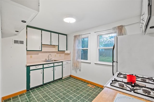 kitchen with visible vents, a sink, light countertops, baseboards, and freestanding refrigerator