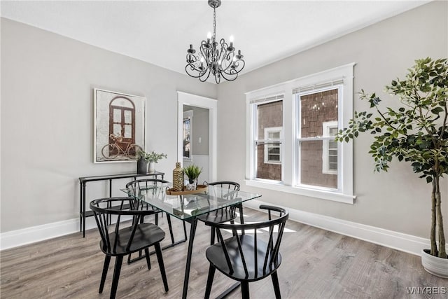 dining room featuring baseboards, light wood-style floors, and a chandelier