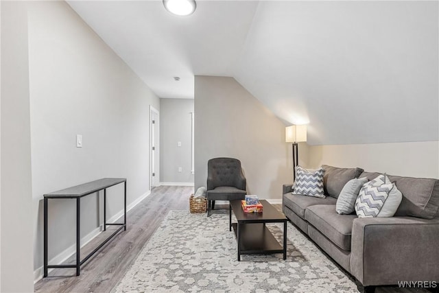living area featuring baseboards, wood finished floors, and lofted ceiling