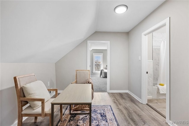 sitting room featuring baseboards, light wood finished floors, and lofted ceiling