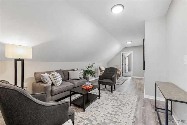 living room with baseboards, light wood-style flooring, and lofted ceiling