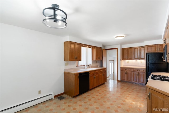 kitchen with light countertops, a baseboard heating unit, brown cabinets, a sink, and black appliances