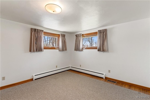 spare room with baseboards, visible vents, a healthy amount of sunlight, and wood finished floors