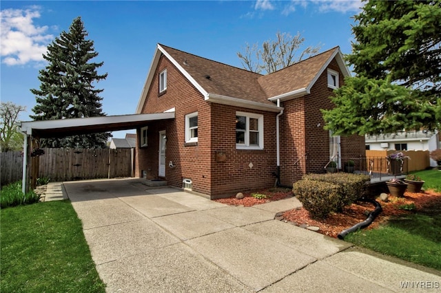 view of side of property with brick siding, fence, concrete driveway, a shingled roof, and an attached carport