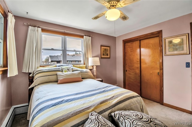 bedroom with a closet, baseboards, baseboard heating, light colored carpet, and a ceiling fan