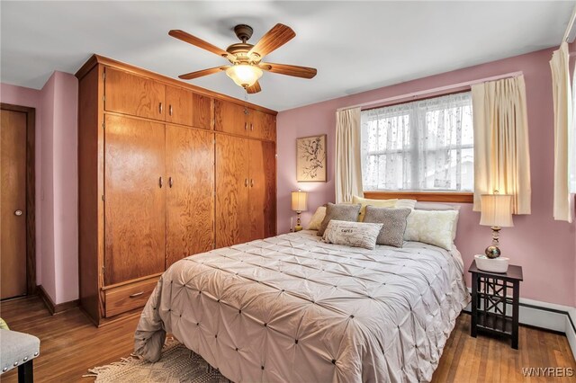 bedroom featuring a ceiling fan, baseboards, a closet, a baseboard heating unit, and light wood-style flooring