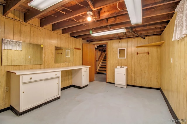 basement featuring baseboards, stairs, and wooden walls