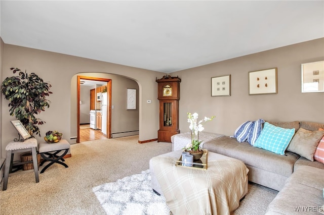 living room with arched walkways, baseboards, light carpet, and a baseboard heating unit