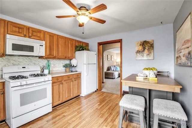 kitchen with white appliances, light countertops, ceiling fan, and light wood-type flooring