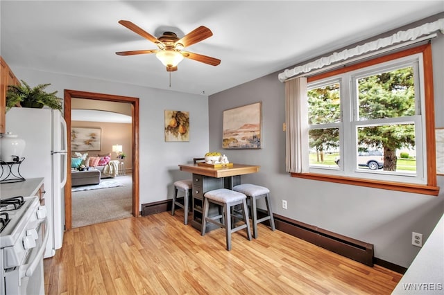 dining room featuring light wood-type flooring, a ceiling fan, baseboards, and baseboard heating