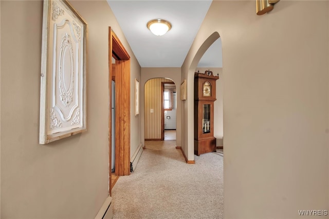 hall with baseboard heating, arched walkways, baseboards, and carpet