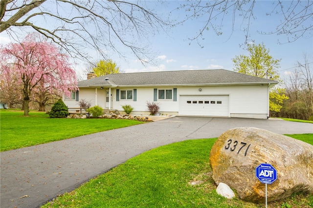 view of front of home featuring an attached garage, a chimney, a front lawn, and aphalt driveway