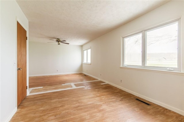 spare room with visible vents, a ceiling fan, baseboards, and light wood finished floors