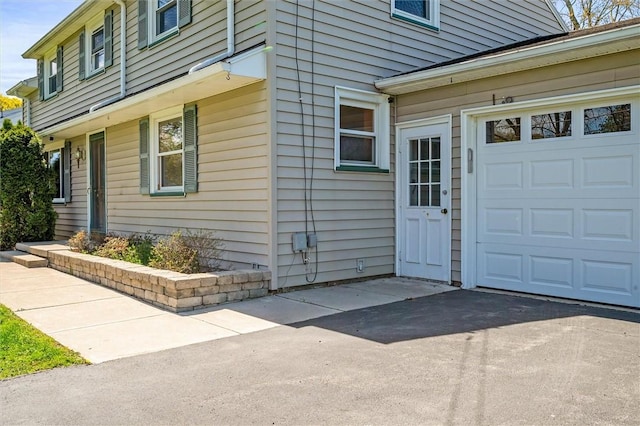 property entrance featuring an attached garage and driveway