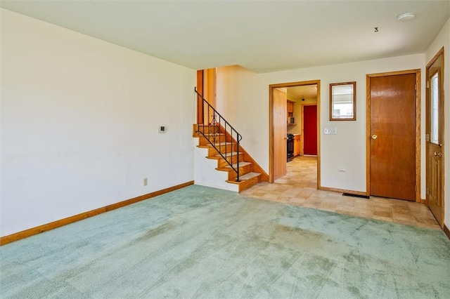 spare room featuring baseboards, stairway, and light colored carpet