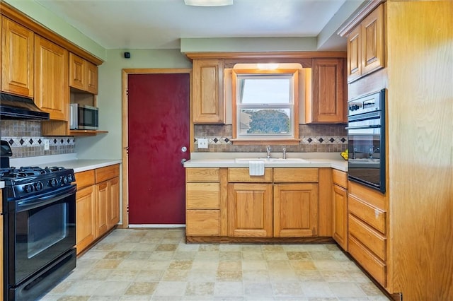 kitchen with wall oven, stainless steel microwave, under cabinet range hood, a sink, and black range with gas cooktop