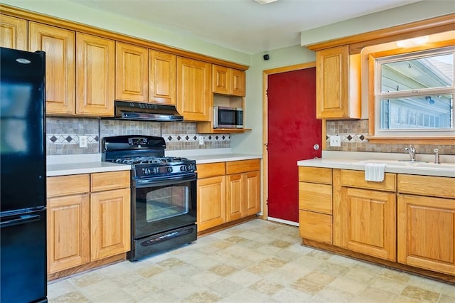 kitchen with light countertops, decorative backsplash, under cabinet range hood, and black appliances