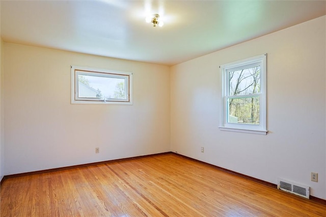 unfurnished room featuring baseboards, visible vents, and light wood-style floors