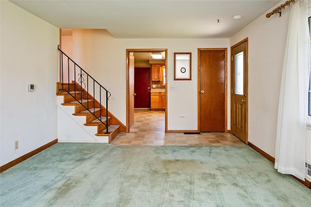 foyer entrance featuring stairway, baseboards, and carpet
