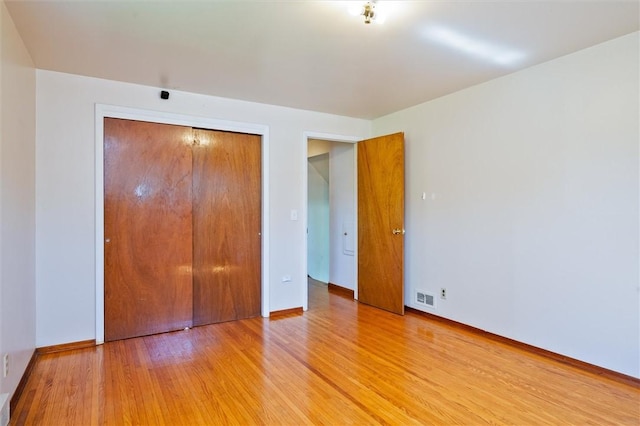 unfurnished bedroom with a closet, baseboards, visible vents, and light wood-type flooring