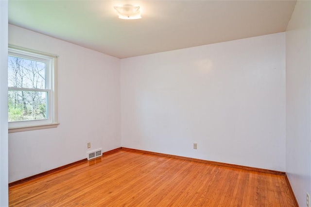 empty room with baseboards, visible vents, and light wood-type flooring