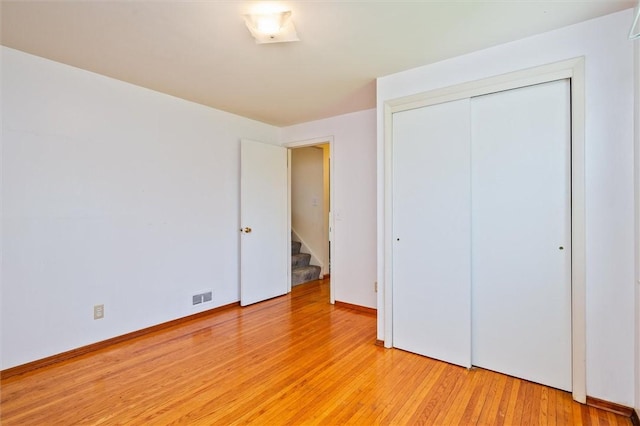 unfurnished bedroom with a closet, visible vents, and light wood-style floors