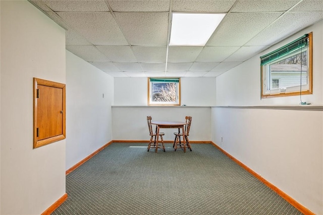 interior space with baseboards, carpet floors, and a drop ceiling