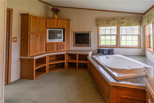 bathroom with ornamental molding, a bath, vaulted ceiling, and carpet flooring