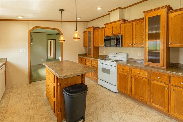 kitchen with brown cabinets, crown molding, arched walkways, stainless steel microwave, and white range with gas cooktop