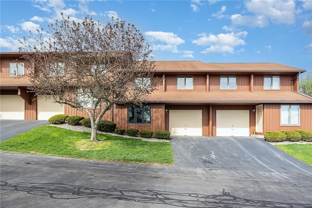 view of property with a garage, driveway, and a front yard