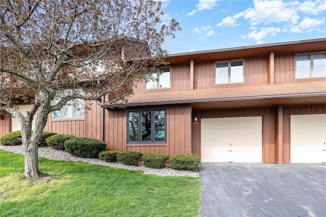 view of property with an attached garage, driveway, and a front yard
