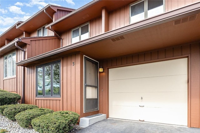 doorway to property featuring a garage, visible vents, and driveway