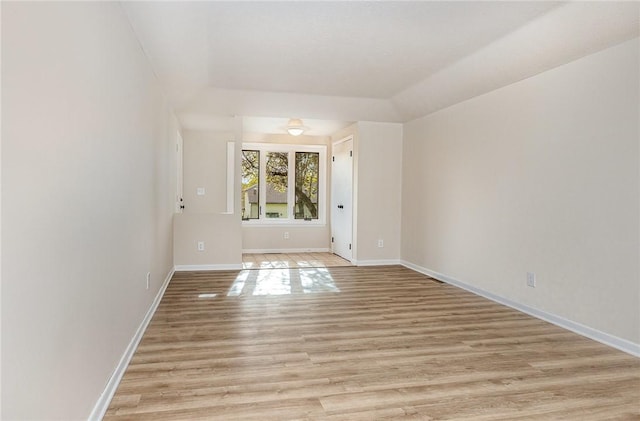 spare room featuring baseboards and light wood finished floors