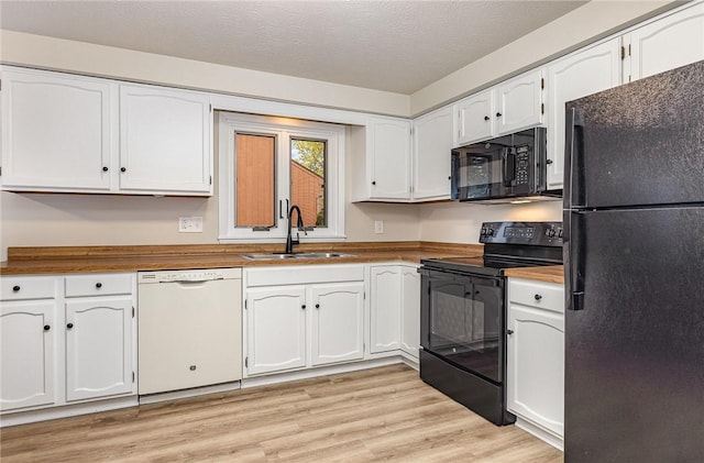 kitchen featuring light wood-style flooring, a sink, white cabinets, black appliances, and butcher block countertops