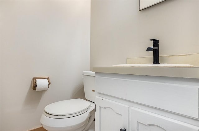 half bathroom with vanity, baseboards, and toilet