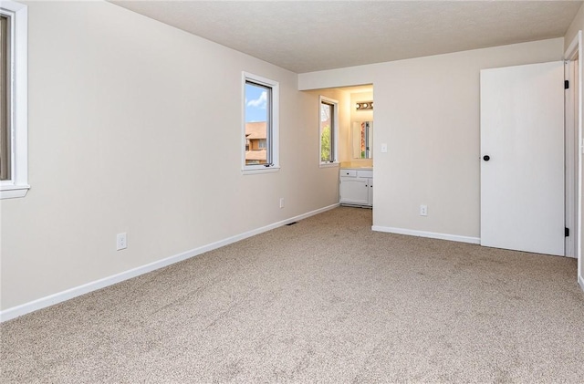 unfurnished bedroom with baseboards, carpet flooring, and ensuite bathroom