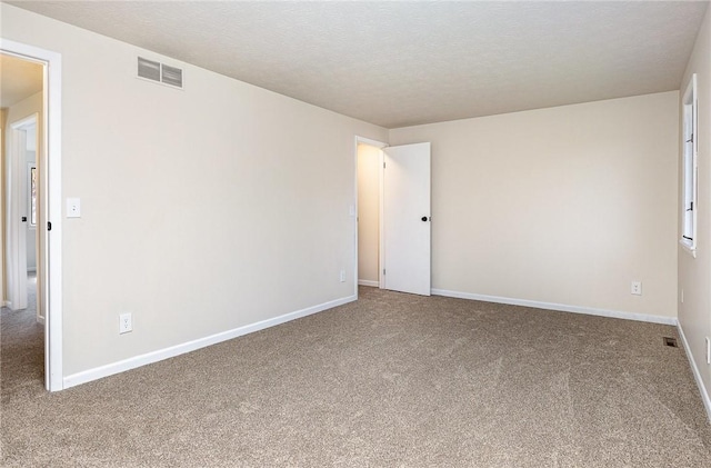 carpeted spare room featuring a textured ceiling, baseboards, and visible vents