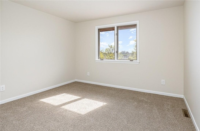 carpeted spare room with visible vents and baseboards