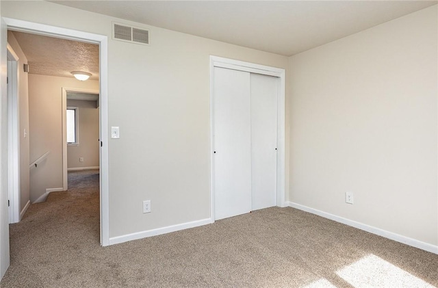 unfurnished bedroom with baseboards, carpet, a closet, and visible vents