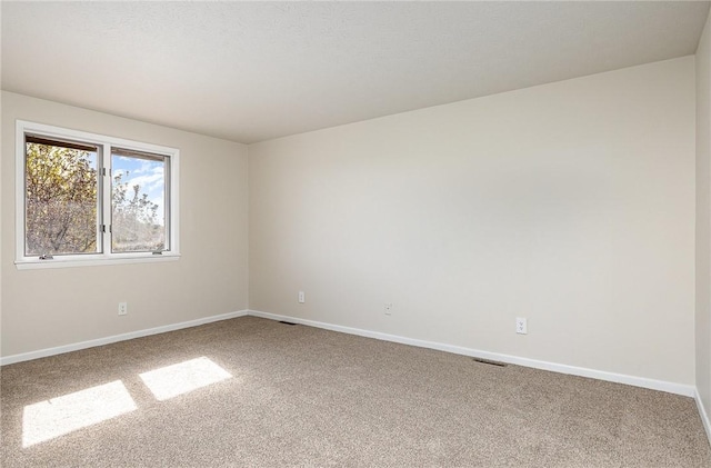 spare room featuring baseboards, carpet flooring, and visible vents