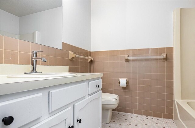 bathroom with a tub, tile walls, wainscoting, and toilet
