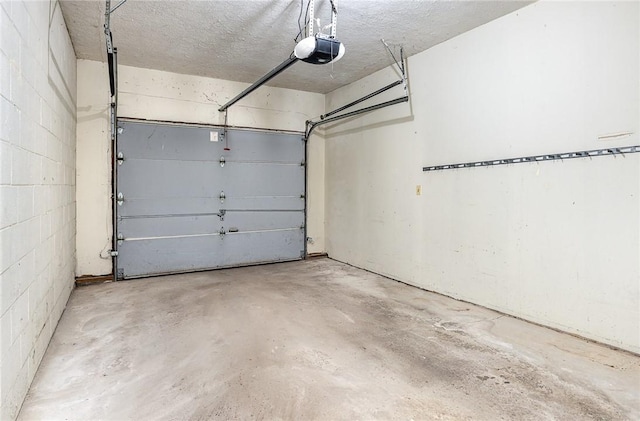 garage featuring concrete block wall and a garage door opener