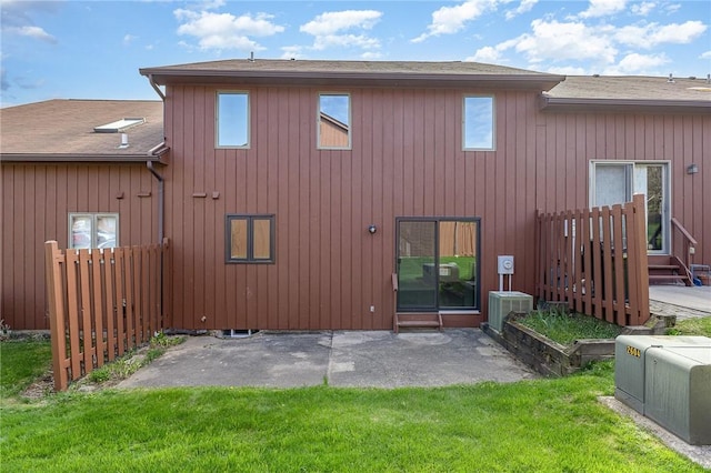 rear view of property with a lawn, a shingled roof, a patio area, and cooling unit