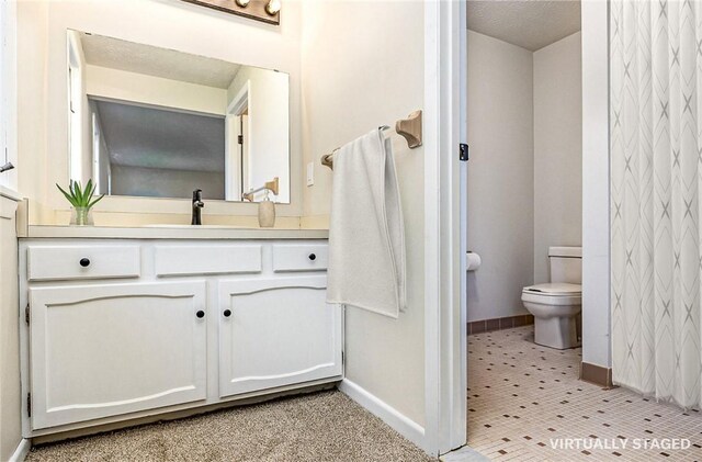 bathroom featuring baseboards, toilet, and vanity